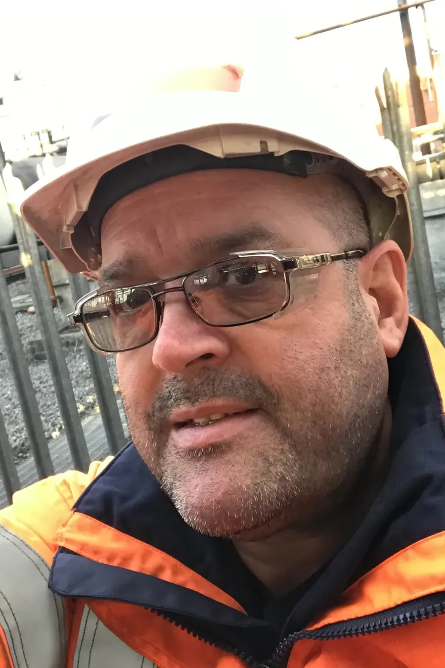 Darren Emery on site in a white hard hat and orange hi-vis jacket